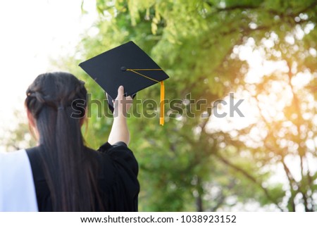 Behind photo of university graduate wears gown and black cap, yellow ribbon and blur bokhe background. 
