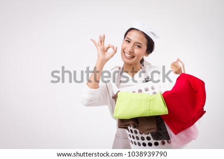 happy smiling asian woman giving yes approval ok hand; good approved, acceptance okay ok hand of domestic helper, woman housekeeper, woman maid holds laundry basket; laundry service staff accepting ok Royalty-Free Stock Photo #1038939790