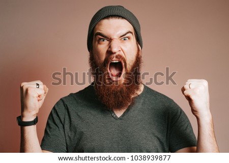 Screaming bearded brutal man and looking at the camera with hands up, Goal, Winner, Celebrating. Face expression. Crazy man with beard. Royalty-Free Stock Photo #1038939877