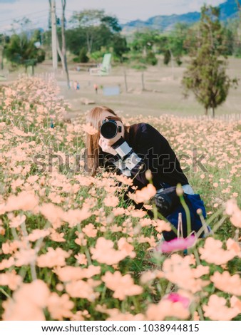 travel and adventure concept portrait from beautiful black long hair photographer asian girl with her camera travel and take photo at flower field with soft focus background