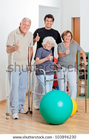 Portrait of disabled senior people with trainer showing thumbs up sign