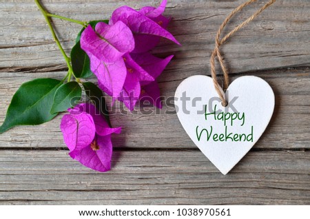 Happy Weekend concept.Bougainvillea flowers and decorative white heart with text on rustic background.Selective focus.