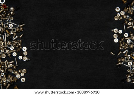 Silvery bolts and screws on a black board background. Flat lay, top view, copy space.