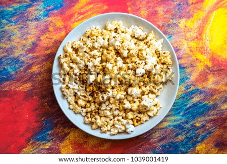 Kitchen poster and table mat design: A white bowl full of popcorn on a bright background. (Horizontal version)