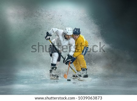 Caucassian ice hockey Players in dynamic action in a professional sport game play around splash drops in hockey under stadium lights.