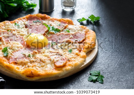Pizza Carbonara on black stone background. Italian Pizza Carbonara with Bacon, Egg and Cheese, copy space.