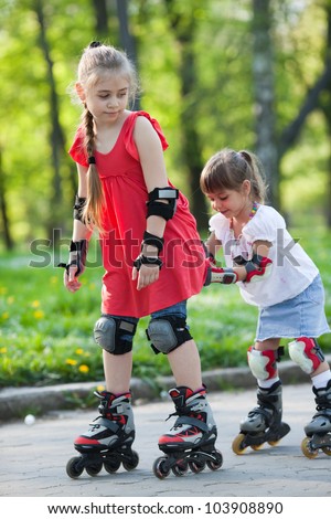 Beautiful little girls on  in-line skates cycling in a park