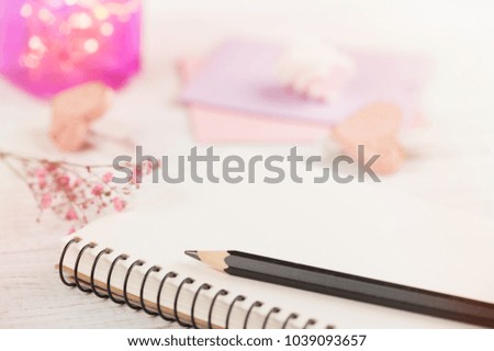 Notebook, flowers and pink lights on wooden background 