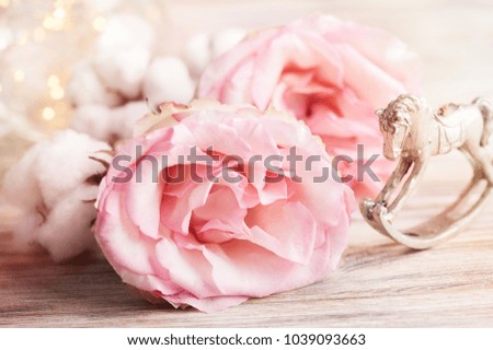 Pink roses and rocking horse with lights on dark wooden background. Greeting card cocept. Toned image