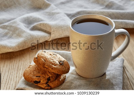 Porcelain teacup with chocolate chips cookies on cotton napkin on a rustic wooden background, top view
