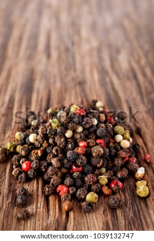 Top view on black, red and white peppercorns isolated on wooden background, shallow depth of field.