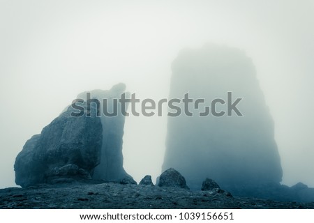 Roque Nublo big rock mountain covered with heavy fog in Gran Canaria, Spain. Futuristic sci fi landscape setting. Thriller, mysterious empty space. Blue effect