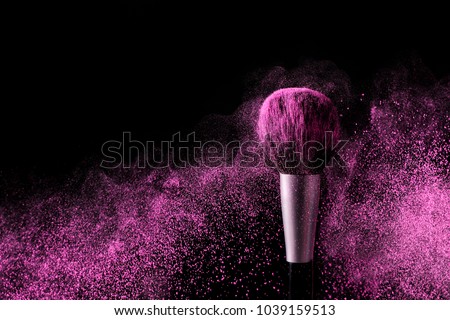 Brush for makeup with purple make-up shadows in motion on a black background. Royalty-Free Stock Photo #1039159513