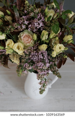 Bouquet of flowers in a jug on a white table on a gray background