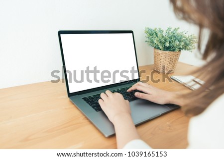 Young Asian woman working using and typing on laptop with mock up blank white screen while at home in office work space. Businesswoman working from home via portable computer. Enjoying time at home.