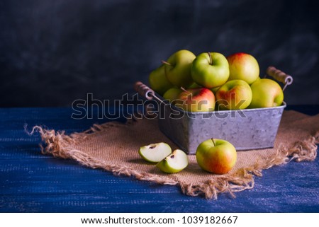 Delicious green apples. In a metal pot. Canvas. Blue textural table, dark background. Healthy natural lifestyle