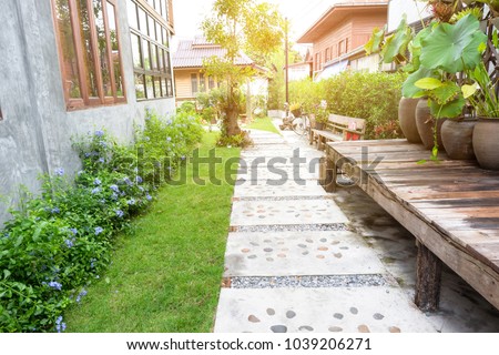 Landscape garden. Stone pathway in tropical garden. Stone walking way made from cement and pebble with green lawn in countryside. Outdoor garden exterior design.