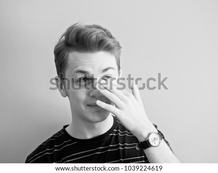 1960s style black and white portrait of young caucasian man. He scratched the bridge of his nose.
