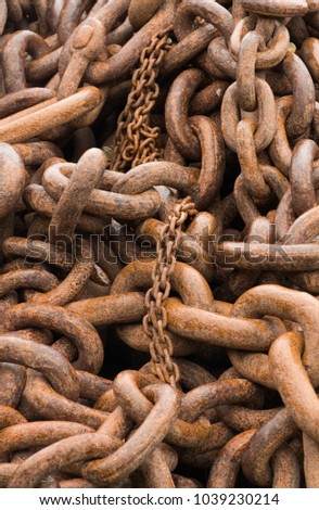 Close up of a pile of rusted chains of two sizes.