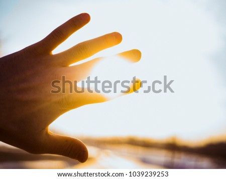 hand raised against sun yellow silhouette
