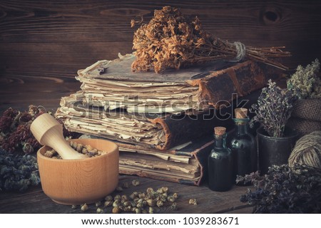 Tincture bottles, bunches of dry healthy herbs, stack of antique books, mortars, sack of medicinal herbs. Herbal medicine. Royalty-Free Stock Photo #1039283671
