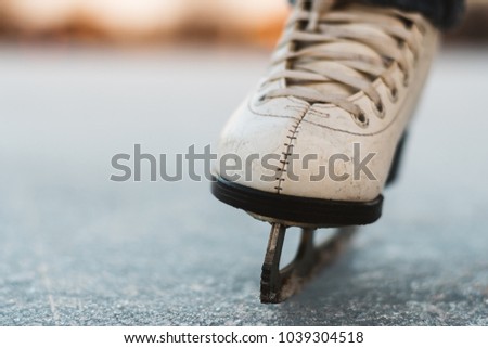 A young girl standing in skates on a frozen pond on ice. Beautiful winter day, nice blurred background.
