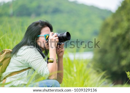 Woman photographer wear sunglasses and holding camera and take a picture of green grass field,Travel wanderlust concept,Banner size leave space for adding text or content for advertise on website.