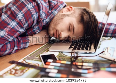 Freelancer man in shirt sleeping at laptop sitting at desk.