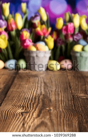 Easter background. Easter eggs, tulips, rustic wooden table. Place for text.