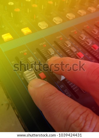 Close Up Man Hand Controlling Audio Mixer, with yellow and Red Light Flare
