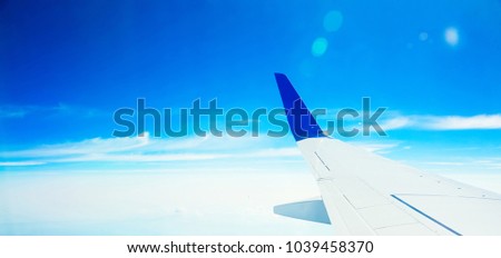 Beautiful View from airplane window in Sunny clear day. Panoramic background With airplane wing flying over clouds high in blue sky. Travel concept. Wide angle Web banner With Copy Space for text
