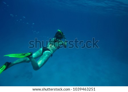 The girl flippers swims in the depths of the blue sea