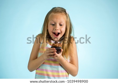 young beautiful happy and excited blond girl 8 or 9 years old holding chocolate cake on her hand looking spastic and cheerful in sugar calories and unhealthy sweet nutrition abuse addiction concept