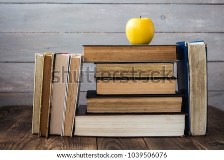 pile of old books and apple on wooden background