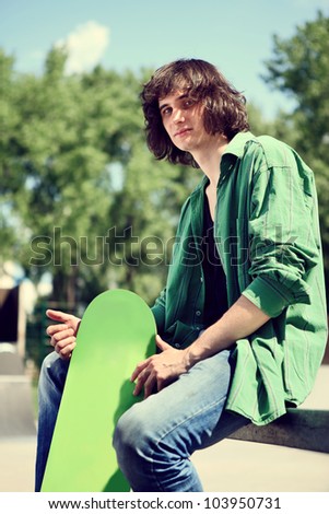 young skater sitting and posing with his skateboard, outdoor