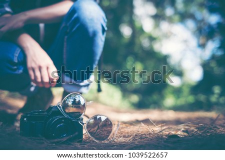 Close up photo Glasses with a camera. Young woman traveller with backpack in a woods. Hiking at summertime.