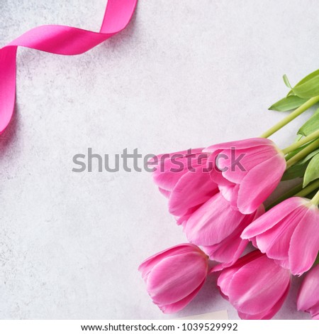 Background with pink tulips and ribbon. Congratulation concept with copy space