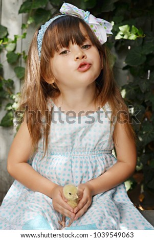 Little cute girl holding fluffy chick and sending a kiss. Happy Easter