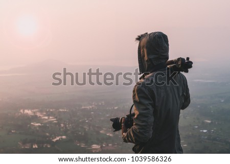 Man traveler photographer and camera taking photo on mountains In the morning the sun rises. Travel Lifestyle hobby concept 