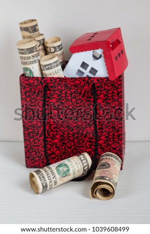 Real estate and mortgage investment. Being an easy way homeowner. Dollars and house in the red bag on the white background.