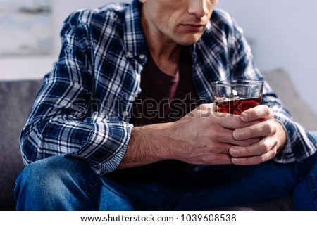partial view of man with alcohol drink sitting on sofa at home Royalty-Free Stock Photo #1039608538