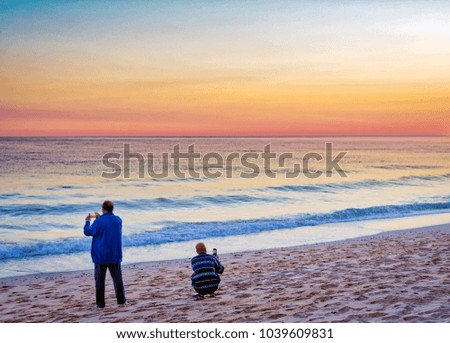 Back view of two people shooting the majestic sky on the beach
