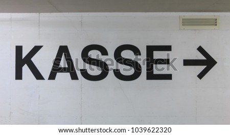 white concrete wall on which is written in German the word cashier (kasse)