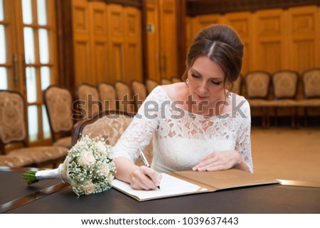A beautiful 40 year old bride signs in a marriage registration book
