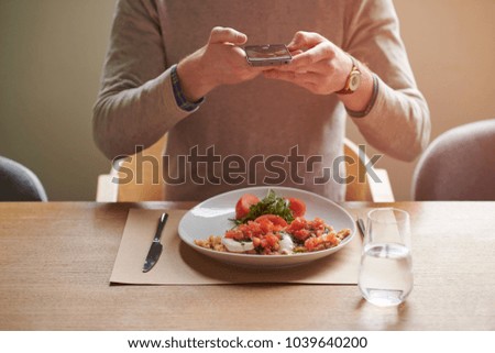 Man taking photos of food with smartphone