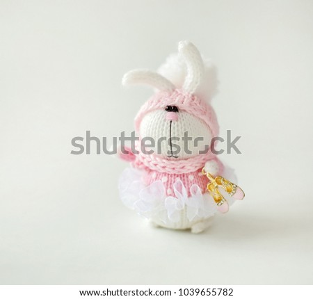 Handmade knitted rabbit. Easter Bunny ballet dancer in pink dress with Pointe shoes in paw on white background