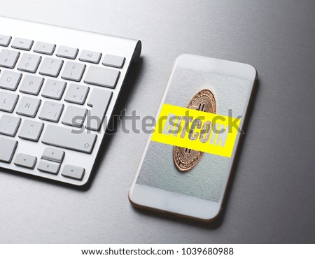 Smartphone with Bitcoin concept on the screen next to keyboard on gray background. Business Concept