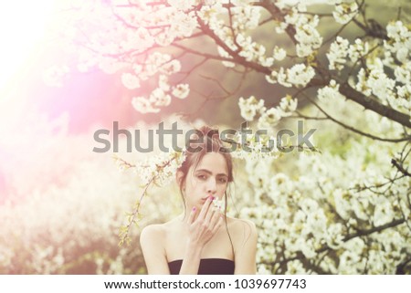 beautiful young woman enjoying smell in a flowering spring garden