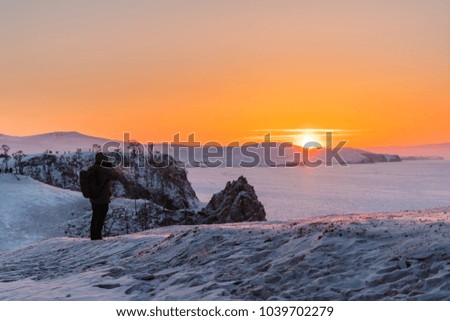 Photographer taking photo of sunset landscape in winter at lake Baikal, Russia. Travelling in winter