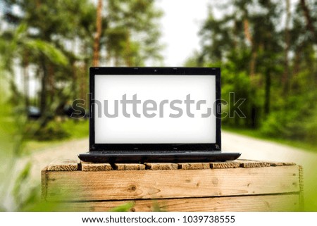 Laptop on wooden box and blurred spring landscape. Free space for your text or photo. 